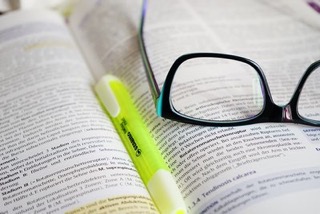 Photo of open book with glasses and a highlighter